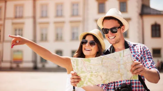 Pareja joven de turistas felices explorando una ciudad con un mapa. Viajes, vacaciones y turismo en pareja