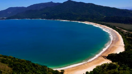 Vista panorámica de la playa de Ponta Negra en Florianópolis, Brasil, con su amplia bahía y exuberante vegetación. Viajes a Brasil, turismo de sol y playa, y escapadas a la isla de Santa Catarina