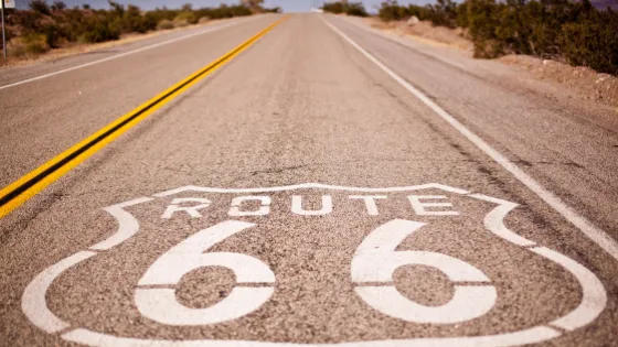 El icónico letrero de la Ruta 66 pintado sobre el asfalto en un camino desértico. Símbolo del turismo de carretera y de los viajes a través de Estados Unidos