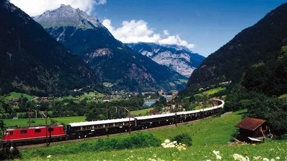 Tren turístico recorriendo un pintoresco valle en los Alpes suizos. Viajes en tren, turismo de aventura y rutas panorámicas por Suiza